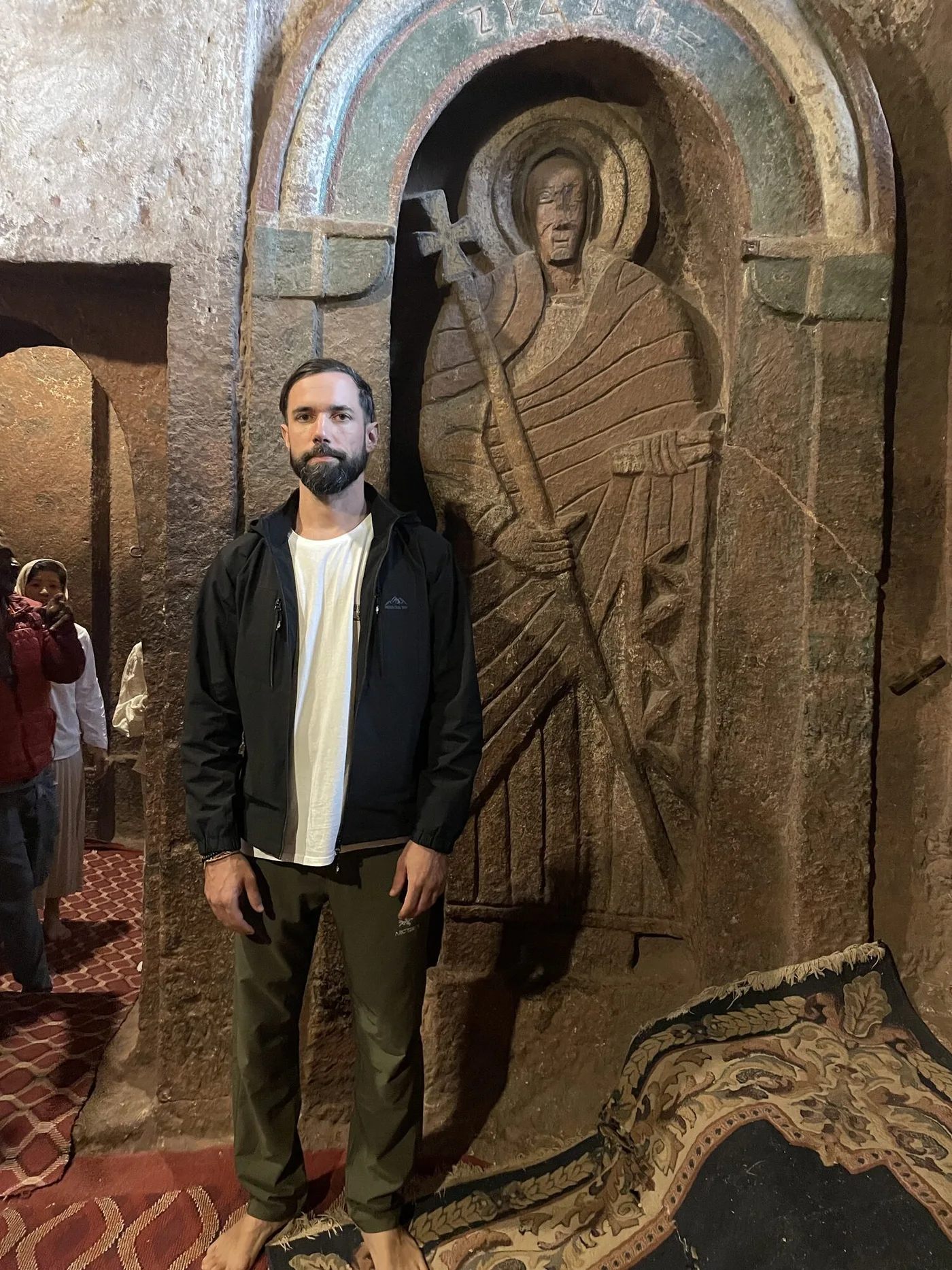 Antonin standing beside a carved saint inside a church in Lalibela
